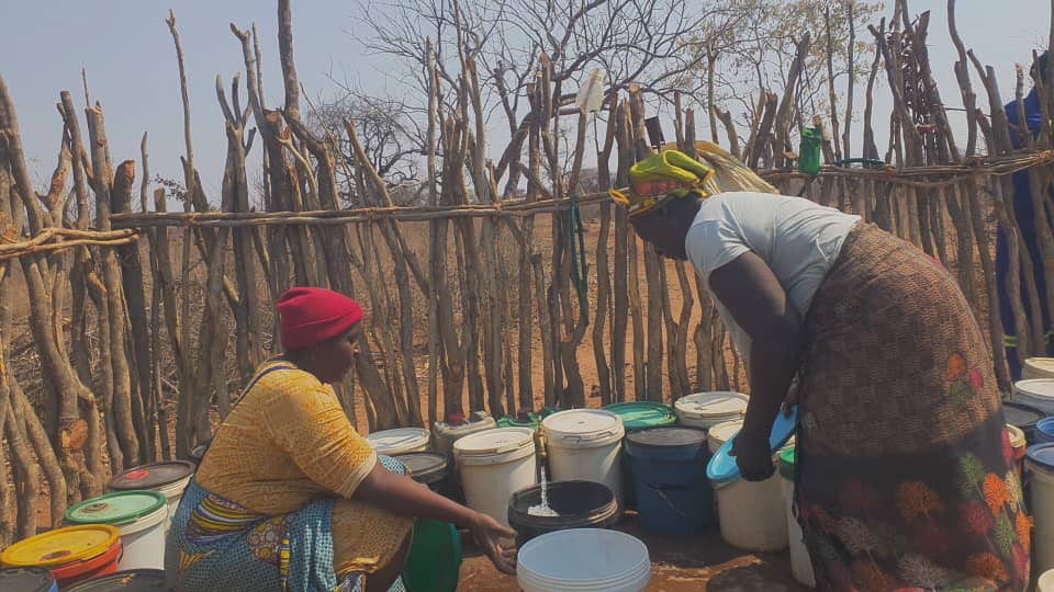 Women collecting water from the Simwenge water point in Binga, Zimbabwe, using buckets and jerrycans
